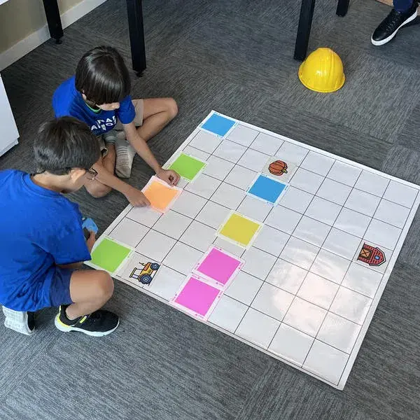 Niños resolviendo reto de programación en tablero