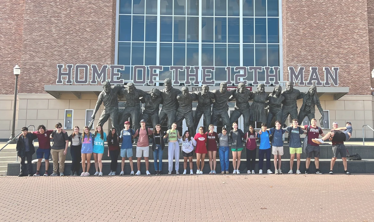 Estudiantes de primer año de una universidad en Estados Unidos frente a una escultura del campus